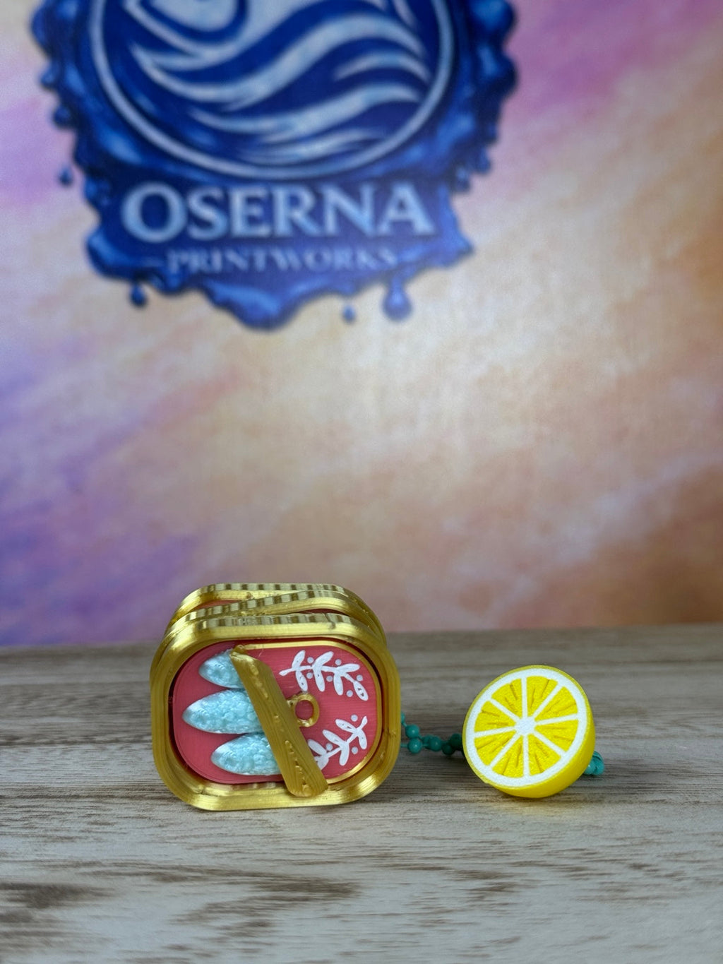 Open sardine tin clicker keychain with lemon charm, front view